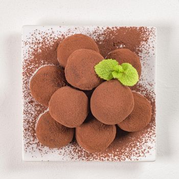 Fine chocolate truffles on white ceramic plate.