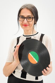 Studio photo of middle aged woman starting getting grey-haired wearing black and white clothes with vinyl record in hands on white background, middle age sexy lady, happy life concept.