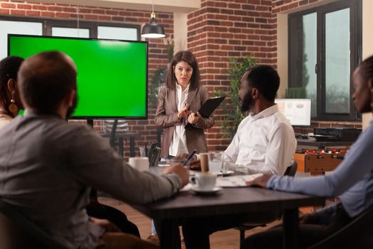 Executive manager woman planning company presentation explaining management strategy to businessteam working in startup office. Mock up green screen chroma key monitor isolated display