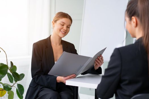 Job interview. Business, career and placement concept. Young blonde woman holding resume, while sitting in front of candidate during corporate meeting. Boss discuss ideas with partner. Handshaking