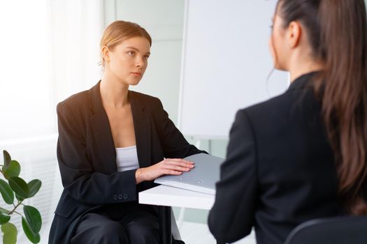 Job interview. Business, career and placement concept. Young blonde woman holding resume, while sitting in front of candidate during corporate meeting. Boss discuss ideas with business partner