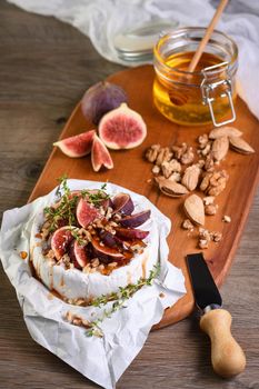 Brie cheese served on a wooden board with figs, walnuts and honey