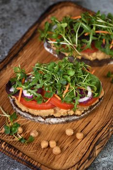  Sandwich toasted rustic bread with chickpea hummus, tomato slices, mix of lettuce and microgreens. Vegetarian breakfast. 