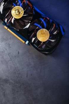 Gold Bitcoin on the video card cooler on a dark background top view. The concept of mining and mining of cryptocurrency, the device of a cryptocurrency farm.