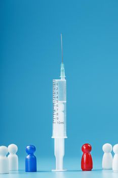 A syringe with a vaccine in the center with a blue and red man with a crowd of whites on a blue background. The concept of a conflict For or Against Vaccination. The danger of the vaccine