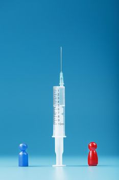 Vaccinate or refuse a syringe with a vaccine with two groups of people a red and a blue human model. The concept of distrust and the dangers of the vaccine