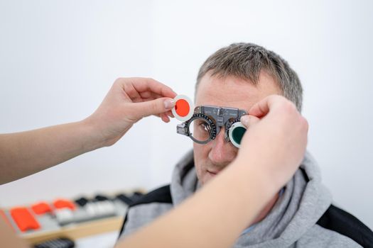 Examining patient vision. Eye exam. Optometrist checking patient eyesight and vision correction. Patient undergoing vision check with special ophthalmic glasses at eye clinic. Selection of eyeglasses.