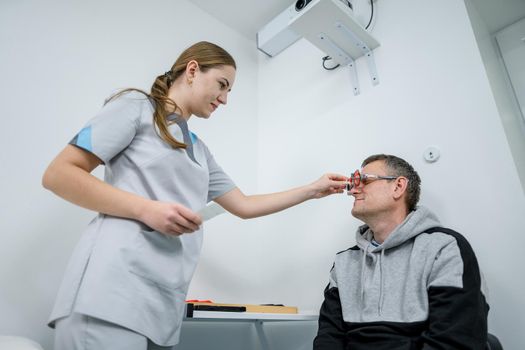 Examining patient vision. Eye exam. Optometrist checking patient eyesight and vision correction. Patient undergoing vision check with special ophthalmic glasses at eye clinic. Selection of eyeglasses.