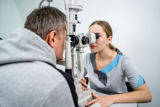 Doctor and patient in ophthalmology clinic. Male patient checking vision with special eye equipment. Optometry concept. Man visiting optician. Patient at slit lamp of optician or optometrist.