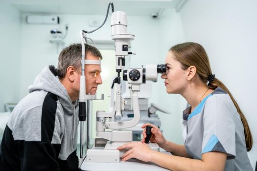 Doctor and patient in ophthalmology clinic. Male patient checking vision with special eye equipment. Optometry concept. Man visiting optician. Patient at slit lamp of optician or optometrist.