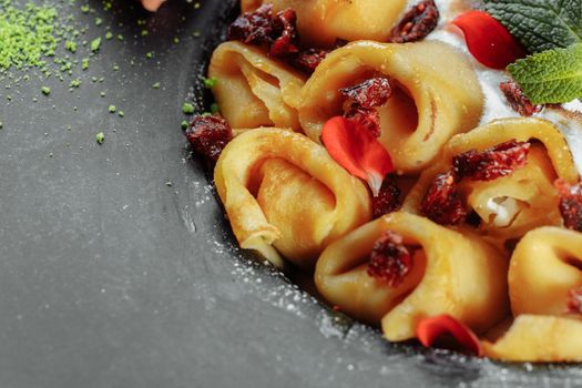 Pancakes with cheese in orange sauce served with caramelized nuts and almonds. Appetizing dish. Culinary photography, a proposal to serve a meal.