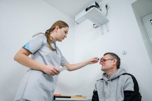 Examining patient vision. Eye exam. Optometrist checking patient eyesight and vision correction. Patient undergoing vision check with special ophthalmic glasses at eye clinic. Selection of eyeglasses.