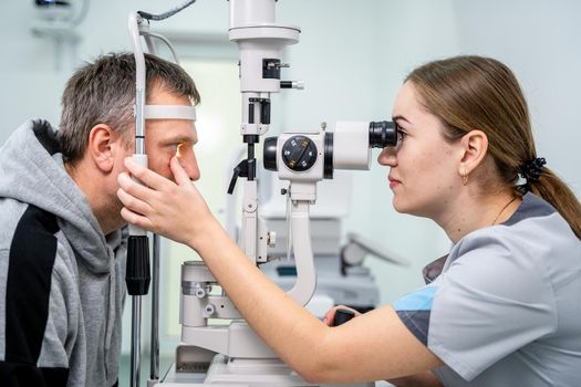 Doctor and patient in ophthalmology clinic. Male patient checking vision with special eye equipment. Optometry concept. Man visiting optician. Patient at slit lamp of optician or optometrist.