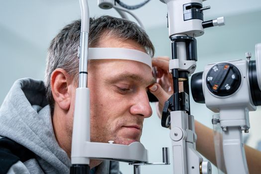 Optometrist examining the eyes of a male patient in a modern ophthalmology clinic. Eye doctor with man patient during an examination in modern clinic. Optometry concept. Eyesight exam in clinic.