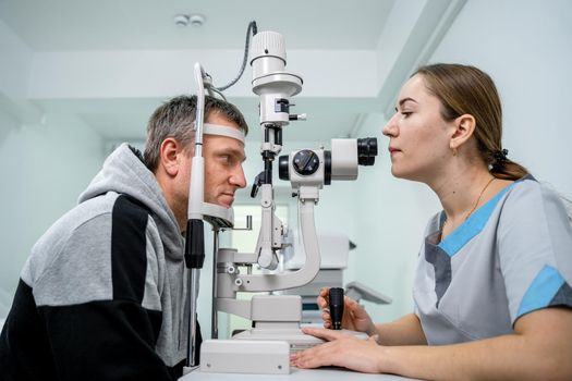 Optometrist examining the eyes of a male patient in a modern ophthalmology clinic. Eye doctor with man patient during an examination in modern clinic. Optometry concept. Eyesight exam in clinic.