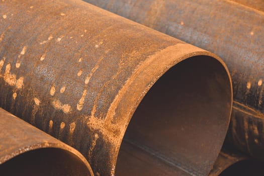 Stack of big rusty steel pipe at a construction site. Installation of pipeline. Metal water tubes. Industrial concept. Soft focus.