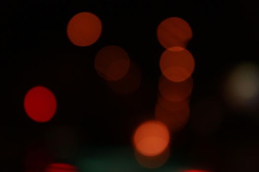 Round red bokeh lights on black background. Defocused city lights