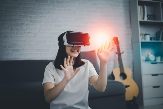 Asian woman play VR game for entertain at home, asian woman joyful  in house on holiday. Happy woman playing metaverse VR technology concept.