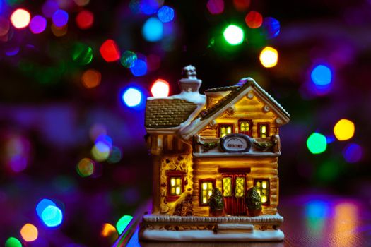 christmas house figure on table on multicolor blurred bokeh background