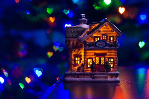 christmas house figure on table on multicolor blurred heart bokeh background