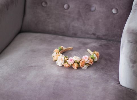 pink and beige floral headband laying on grey velour chair background