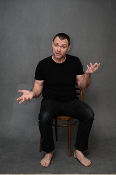portrait of a man sitting on a chair talking with emotions to the camera