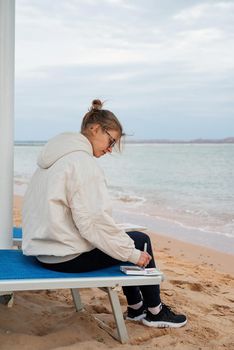 Hobbbies and leisure. young woman artist painting or doing travel sketches using watercolor by the seaside