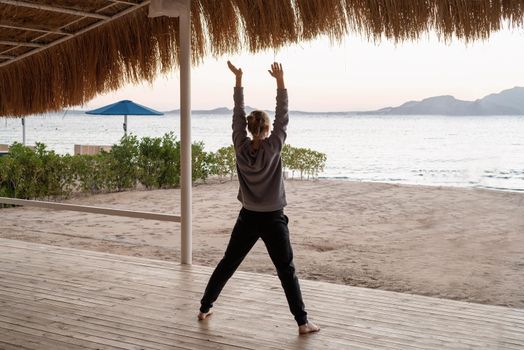 Health and wellness. Young healthy woman practicing yoga on the beach at sunset