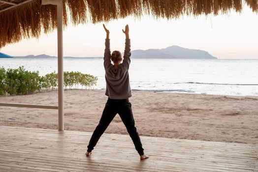 Health and wellness. Young healthy woman practicing yoga on the beach at sunset