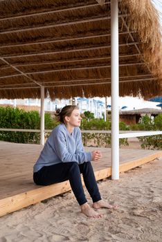 Health and wellness. Young woman in sport clothes enjoying sunrise sitting at the beach