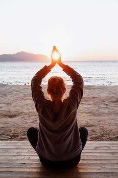 Health and wellness. Young healthy woman practicing yoga on the beach at sunset