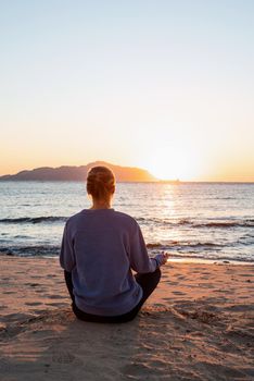 Health and wellness. Young healthy woman practicing yoga on the beach at sunset