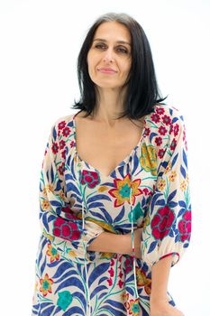Studio portrait of middle aged woman starting getting grey-haired wearing dress with flowers on white background, middle age sexy lady, cosmetology concept.
