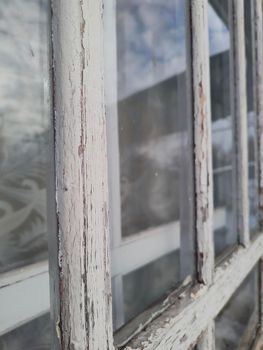 Old window with peeling white paint on the frame focus on foreground window perspective