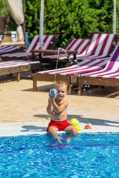 the child sits near the pool is played with a water pistol. selective focus