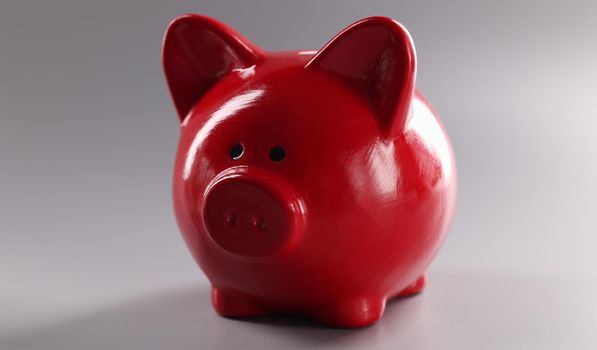 Closeup of red piggy banks for coins on gray background. Cash savings concept