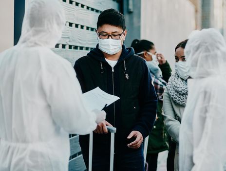 Shot of a young man talking to a healthcare worker in a hazmat suit during an outbreak