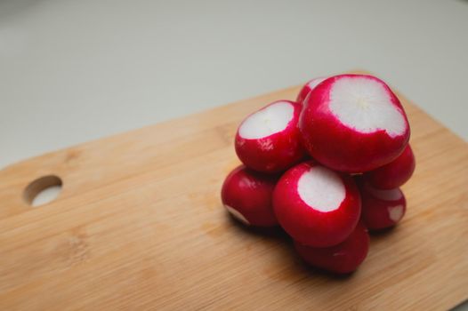 Close-up of partially peeled radishes in a pile on a wooden board. Vegetarian salad ingredient. Vegan food.