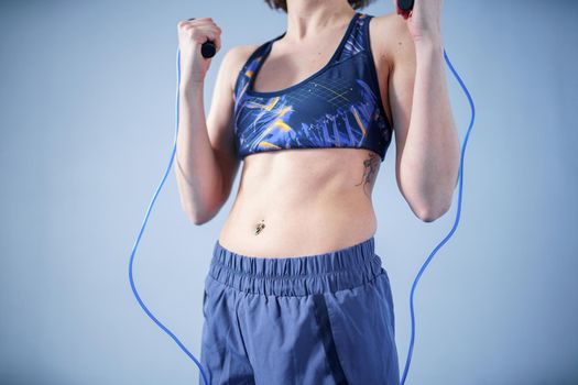 Smiling sportswoman posing with a skipping rope. Female with muscular body posing with jump rope. Fitness model. Body positivity, sport, fitness concept. Healthy lifestyle. Fit woman with jump rope.