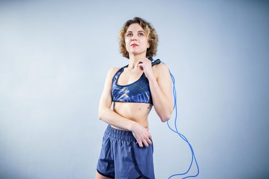 Smiling sportswoman posing with a skipping rope. Female with muscular body posing with jump rope. Fitness model. Body positivity, sport, fitness concept. Healthy lifestyle. Fit woman with jump rope.