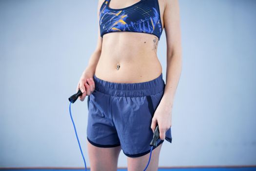 Smiling sportswoman posing with a skipping rope. Female with muscular body posing with jump rope. Fitness model. Body positivity, sport, fitness concept. Healthy lifestyle. Fit woman with jump rope.