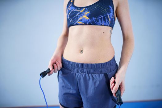 Smiling sportswoman posing with a skipping rope. Female with muscular body posing with jump rope. Fitness model. Body positivity, sport, fitness concept. Healthy lifestyle. Fit woman with jump rope.