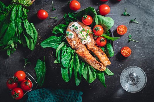 A plate with fresh green raw spinach and fried wild salmon, tomatoes and cream cheese sauce High quality photo