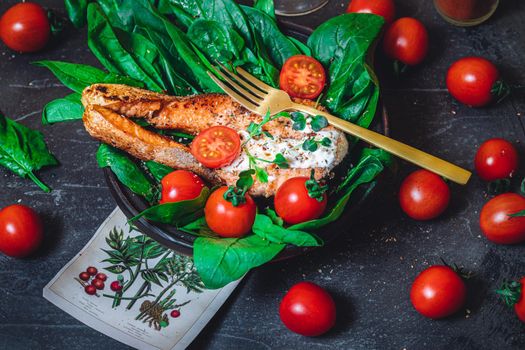 A plate with fresh green raw spinach and fried wild salmon, tomatoes and cream cheese sauce High quality photo