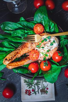 A plate with fresh green raw spinach and fried wild salmon, tomatoes and cream cheese sauce High quality photo