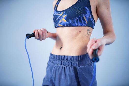 Smiling sportswoman posing with a skipping rope. Female with muscular body posing with jump rope. Fitness model. Body positivity, sport, fitness concept. Healthy lifestyle. Fit woman with jump rope.