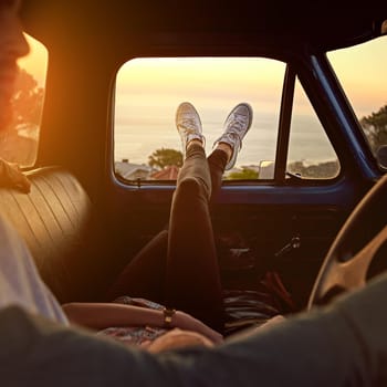 Shot of a young woman relaxing on her boyfriends lap with her feet up during a road trip