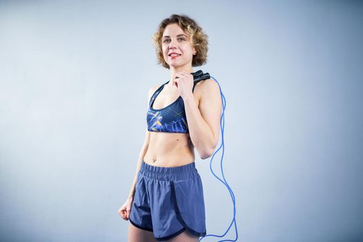 Smiling sportswoman posing with a skipping rope. Female with muscular body posing with jump rope. Fitness model. Body positivity, sport, fitness concept. Healthy lifestyle. Fit woman with jump rope.