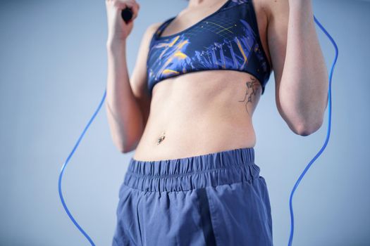 Fit woman with jump rope posing in the gym. Sport exercises healthy lifestyle concept. Sporty happy woman with skipping rope posing to the camera. Active lifestyle concept. Healthy lifestyle.