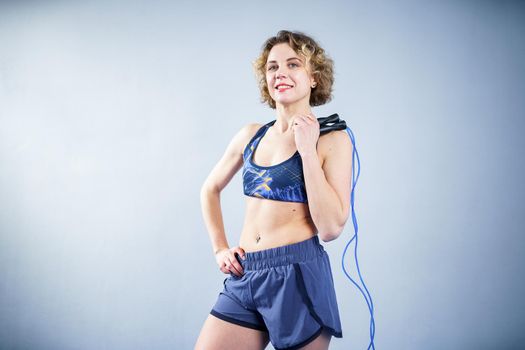 Smiling sportswoman posing with a skipping rope. Female with muscular body posing with jump rope. Fitness model. Body positivity, sport, fitness concept. Healthy lifestyle. Fit woman with jump rope.